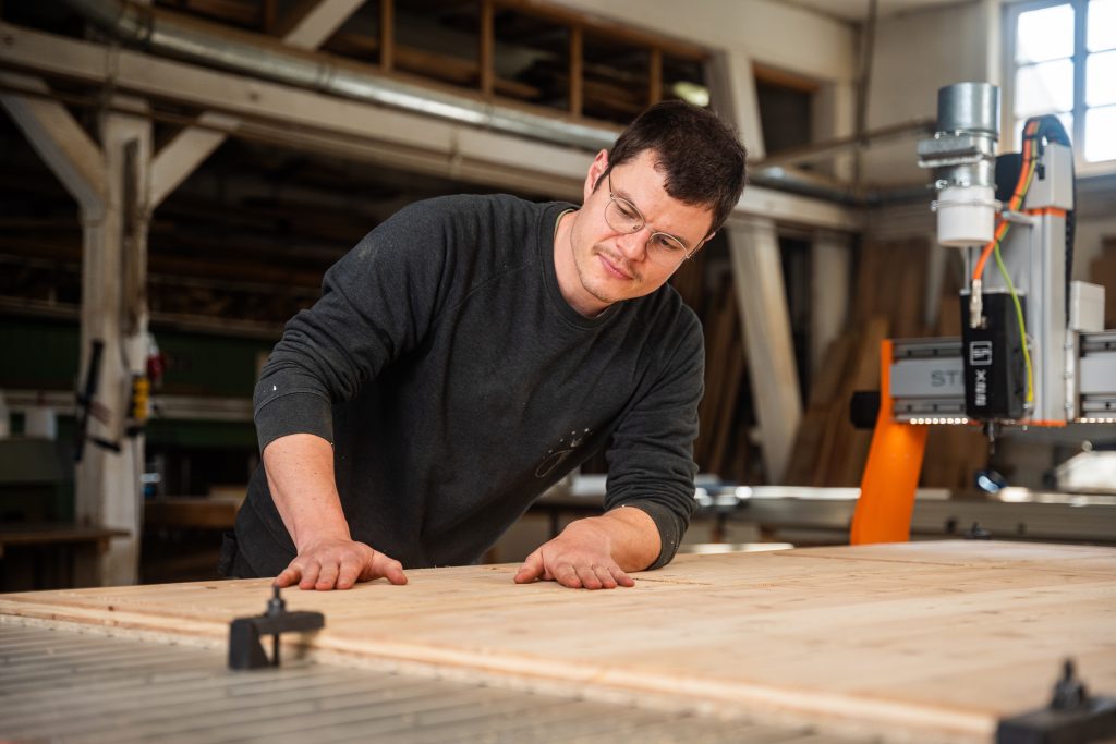 Tischler bearbeitet große Holzplatte auf der CNC Maschine